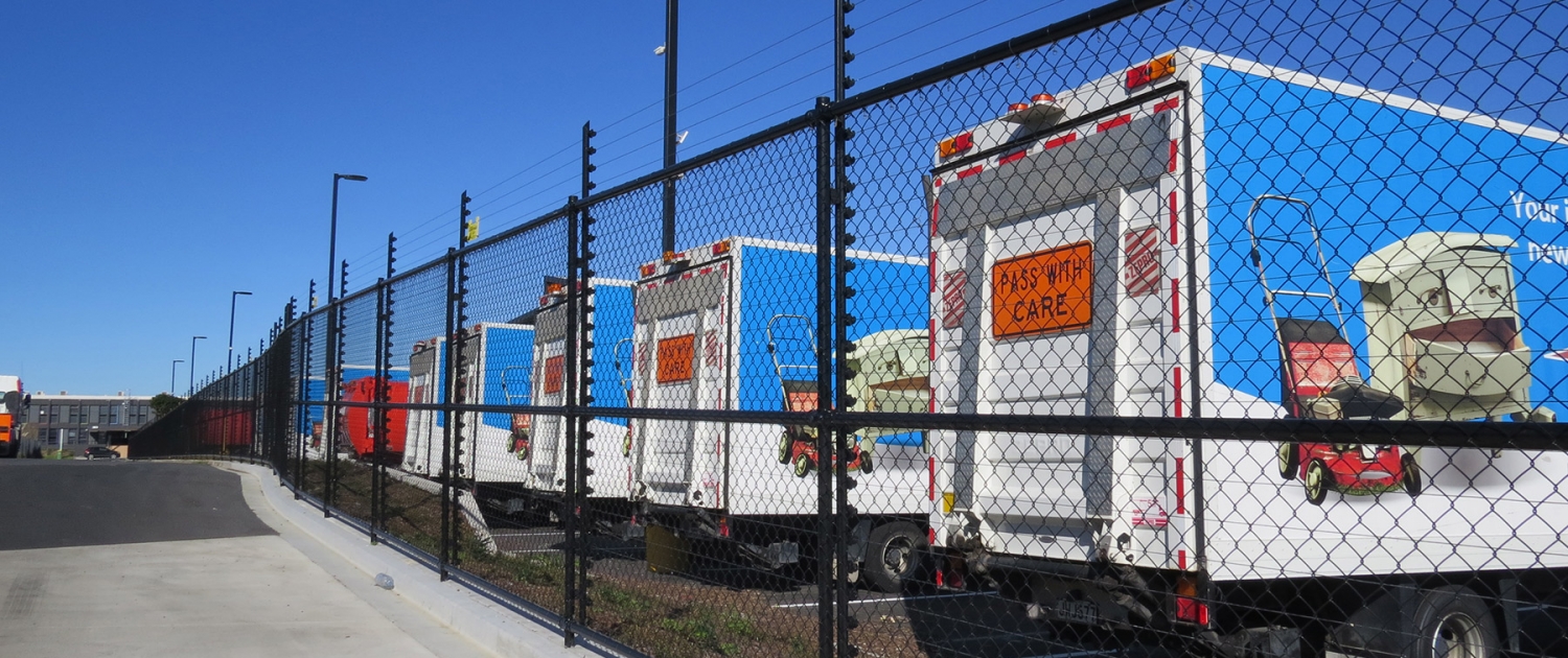 Image showing a row of waste management trucks behind a Fencerite chainlink security fence