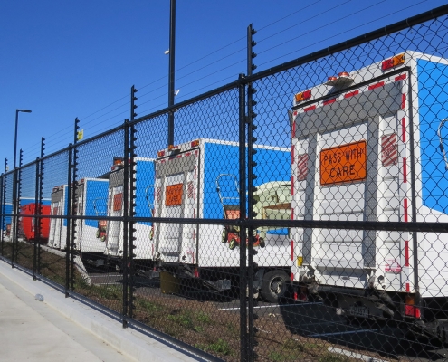 Image showing a row of waste management trucks behind a Fencerite chainlink security fence