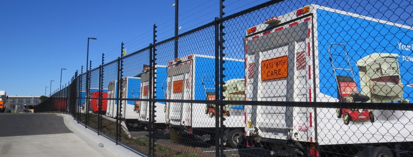 Image showing a row of waste management trucks behind a Fencerite chainlink security fence