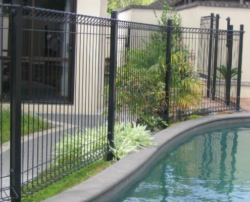 Image showing a curving residential swimming pool surrounded by pool fencing