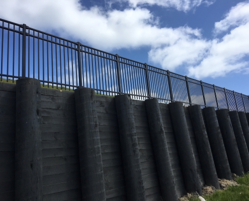 Image showing the view looking up at the top of a retaining wall, with black balustrades, installed by Fencerite