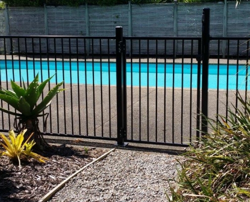 Image showing black aluminium pool fencing and gate, enclosing a modern swimming pool area in residential grounds