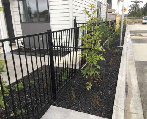 Image showing a black aluminium fence surrounding a residential building with gardens, installed by Fencerite