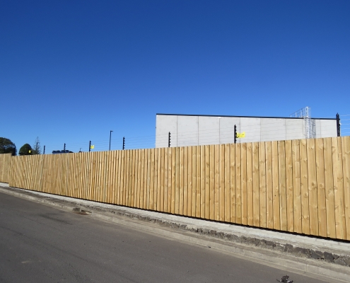 Image showing a wooden security fence surrounding an industrial building, installed by Fencerite