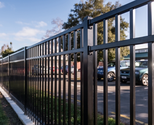 Image showing a close up view of black aluminium school fencing, bordering a school carpark