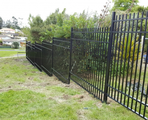 Image showing black aluminium school fencing, bordering school grounds, going down a grassy hill