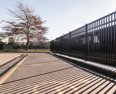 Image showing a school carpark with bordering black aluminium school fencing, installed by Fencerite