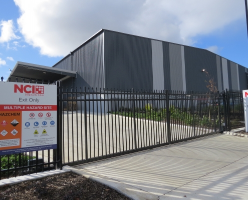 Image showing a black aluminium security sliding gate, in front of the NCI Packaging building in Auckland, installed by Fencerite