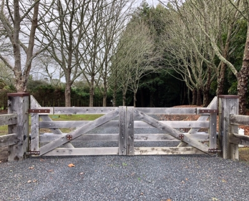 Image showing a wooden gate at the entrance of a rural driveway, installed by Fencerite